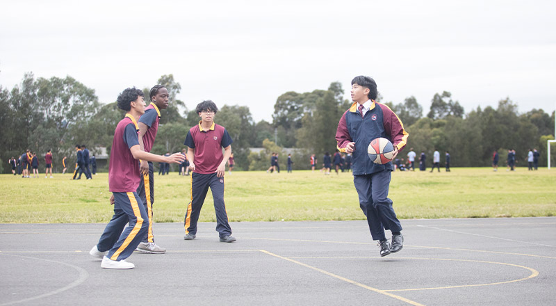 Students playing basketball on the basketball courts at St John XXIII College Stanhope Gardens