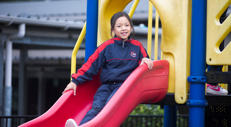 Student sliding down the slide on the playground at St John XXIII College Stanhope Gardens