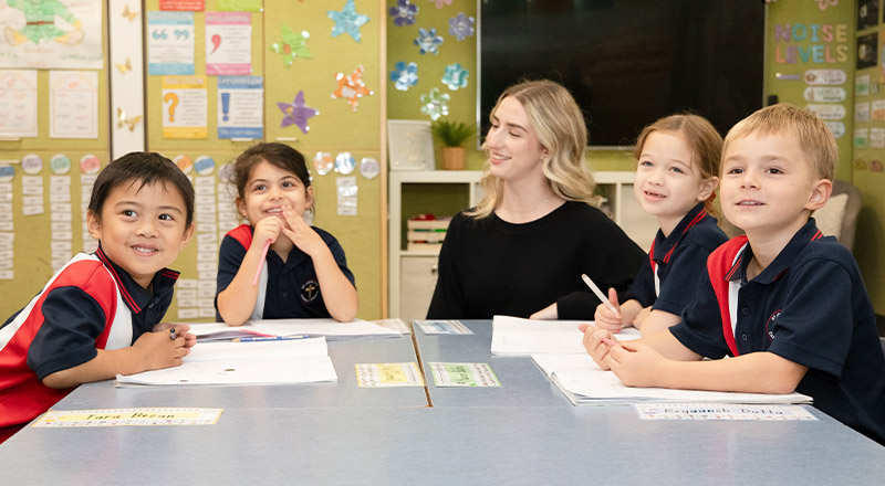 Teacher with her students in the classroom at Students reading a book in the library at St John XXIII College Stanhope Gardens