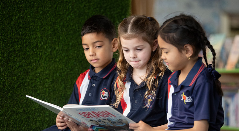Students reading a book together in the library at St John XXIII College Stanhope Gardens