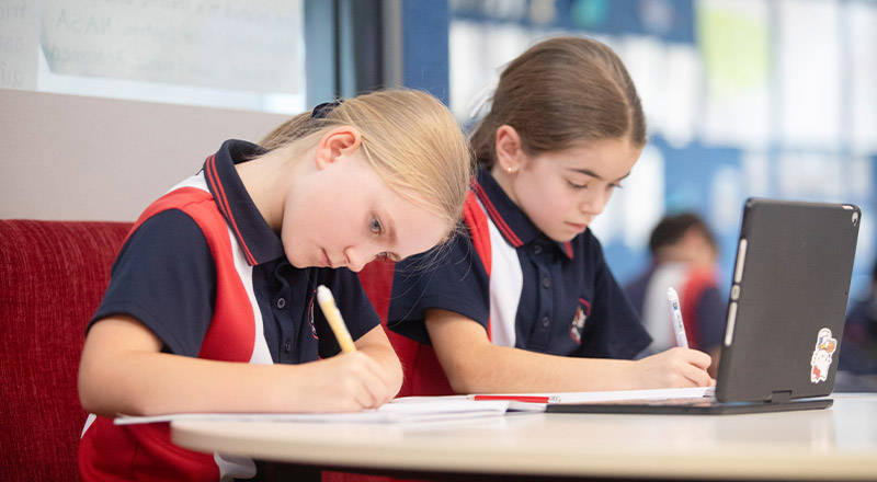 Students working together in the classroom at Students reading a book in the library at St John XXIII College Stanhope Gardens
