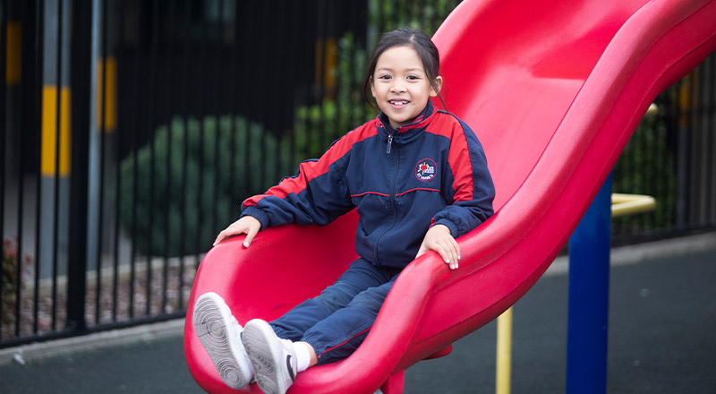 Student sliding down a slide in the playground at St John XXIII College Stanhope Gardens