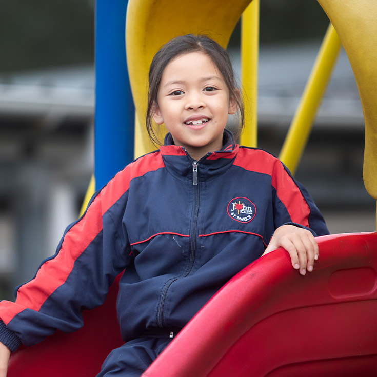Student sitting on the slide in the playground at St John XXIII College Stanhope Gardens